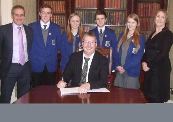 DUP Finance Minister Sammy Wilson MLA was a guest speaker at St. Killian's recently. He is pictured with Mr J Brady, principal, and Mrs E McKay, vice-principal signing the visitors book along with the head boy and giirl and their deputies. INNT 06-653-CON
