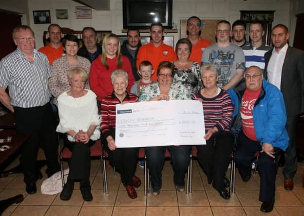 Irene French (seated centre) presents a cheque for £1500 to Margaret McKee and Carol Hill of Cancer Research, money raised from a joint effort between the Diamond Bar and the Fairhill Bar in Ahoghill. The Diamond held a charity darts tournament and the Fairhill staged a charity music evening. Included are John Small (Diamond Bar), Gareth Montgomery (Fairhill Bar), friends and supporters of both events. INBT06-232AC