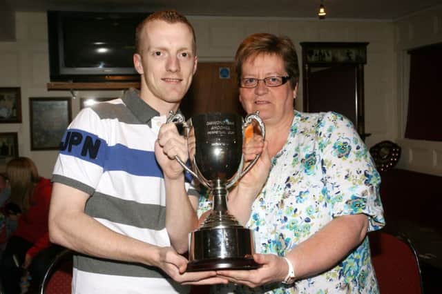 Ashley Rainey, winner of the Diamond Bar (Ahoghill) Perpetual Cup from the first charity Trevor Turtle Memorial Darts competition, is pictured receiving his award from Irene French (Trevor's sister). INBT06-233AC