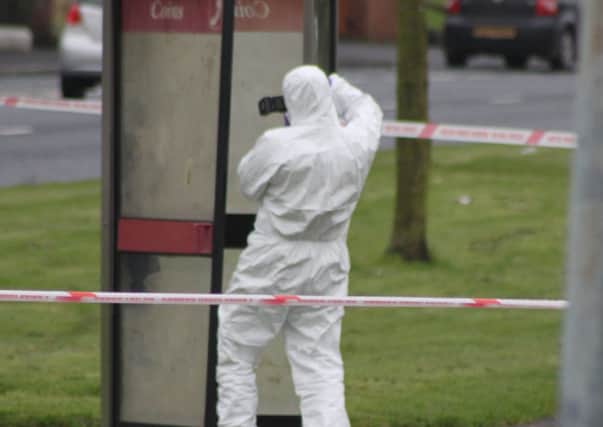 A police forensics officer pays close attention to a phone box at Russell Drive on Sunday afternoon as a murder investigation got underway. INLM0612-807ca