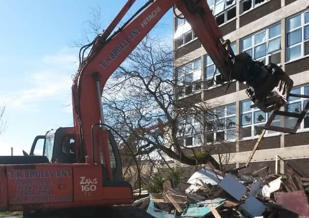 A track digger crushes and moves debris at the former St Peter's High School.