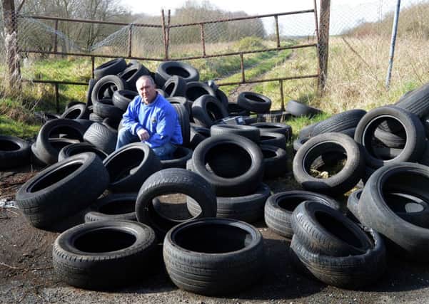 SDLP Councillor Declan McAlinden pictured with the tyres which were dumped on Annaloiste Road, near Oxford Island. INLM11-214.