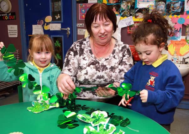 Alesha Fleming and Mia Grieve, help playgroup leader Mary McCloskey, prepare St. Patricks Day decorations at the Little Diamonds Community Playgroup, Claudy. 1114-005MT.