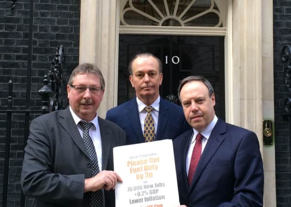 MPs Sammy Wilson and Nigel Dodds with motoring journalist Quentin Wilson (centre) with the fuel duty petition that was handed in at 10 Downing Street. INLT 12-670-CON