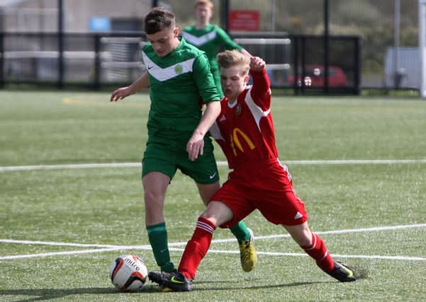 Carniny U-16 player Christian Jaworski manages to kick the ball away from his Foyle opponent. INBT16-269AC
