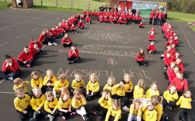 WE'RE IN THE MONEY. Pictured are pupils from Bushmills PS and Nursery Unit, who took part in a 'Penny Trail' during Money Week on Friday. The boys and girls created the school's crest with coins. Looking are are Principal Jane Logan and staff.INBM17-14 045SC.