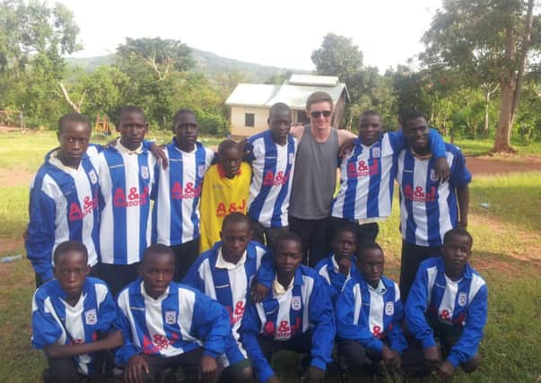 Ross Kerr and the children from the 'Light for All' Secondary School Uganda wearing the football Kit donated by the Moneyslane Club