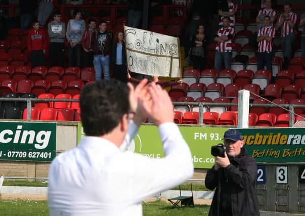COLLINS OUT!. . . . Derry manager Roddy Collins acknowledges the crowd at the end of yesterday's clash with Limerick as a lone supporter unfurls a 'Collins Out' banner. DER1714JM038 (Photo: Jim McCafferty)