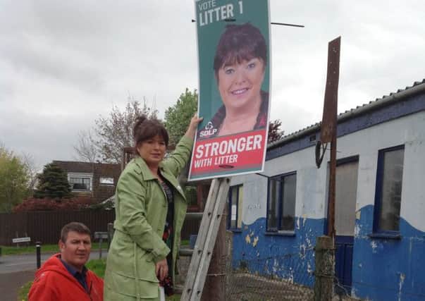SDLP candidate Maureen Litter with her husband Ed replacing a poster after another was torn down