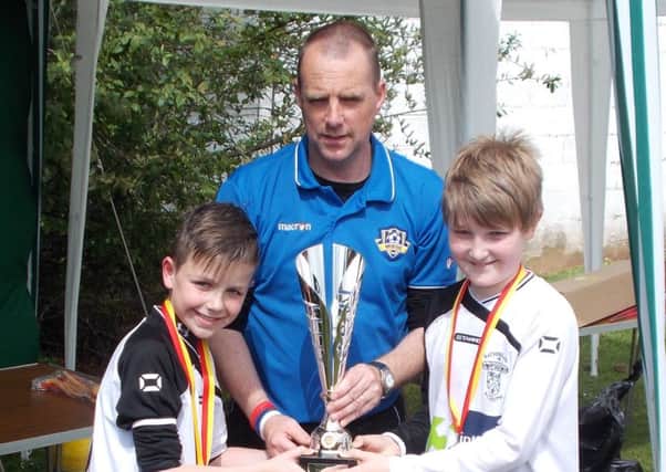 Captain Thomas Ingram and top scorer Caolan Teer receive the trophy from Michael O'Kane of the Mid Ulster League.