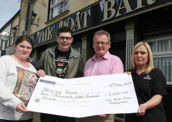 Nigel Carney, of Helping Hands, receives a cheque for £2100 from Christine Balmer, Bobby Letters and Diane Stewart, proceeds of a recent Garth Brooks tribute night held in The Moat Bar. INBT21-203AC