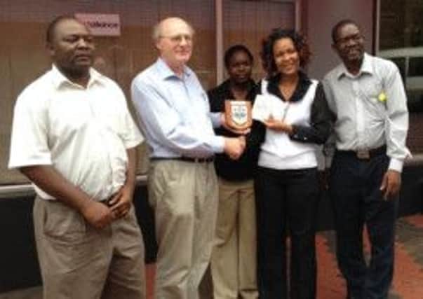 Canon George Irwin presents a Lisburn City plaque of staff at one of the Christian Aid projects in Zimbabwe.