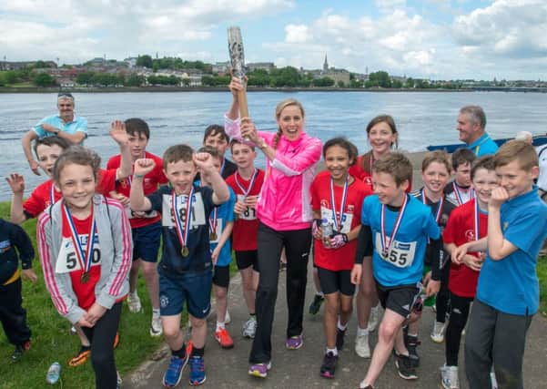 The Queen's Baton Relay arrives at Prehen in Londonderry carried by triathlete Aileen Reid after being rowed up the River Foyle on wednesday afternoon. Children who took part in a Derry City Council Duathlon provided a guard of honor to welcome the relay.