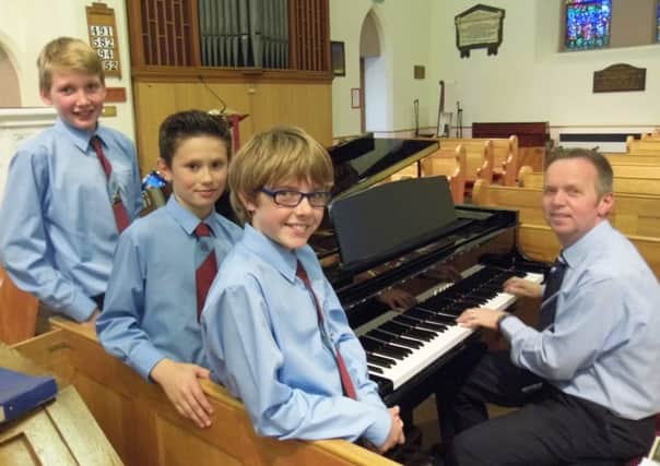 Geoffrey Cherry playing the grand piano sponsored by A.A Music with three leading members of the Pond Park Primary School Senior Choir.