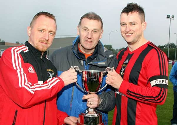 Alex Rainey presents the Rainey Cup to Harryville Homers captains Geoff Mitchell and Ian Russell after the Harryville side landed their sixth trophy of the season by beating Clough Rangers.