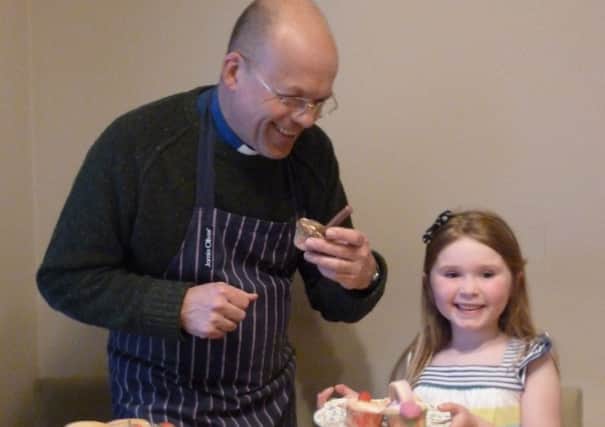 Roger Thompson, rector of St Patrick's with All Saints, enjoys sampling a cupcake baked by six-year-old Sophia Woods. INLT 23-661-CON