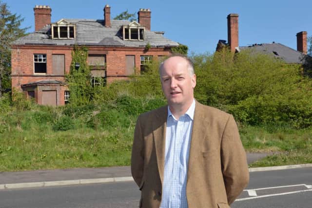 Councillor Tom Campbell pictured in front of the derelict former school buildings on Jordanstown Road.