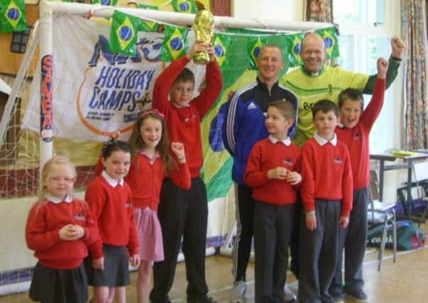 Wesley Gregg, IFA Grassroots Development Officer and Rev Roger Thompson present the replica World Cup to Ava, Ularia, Isla, David, John, Ryan and Daniel at Cairncastle Primary School.  INLT 25-681-CON