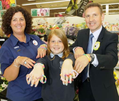 BAND OF GOLD. Lislagan P7 pupil, Rhianna Todd displays the 'Loom Bands' she created  along with Jackie Brogan, Tesco Community Champion and Store Manager Geoff Purcell which raised £106.00 for Diabetes UK by selling her product in memory of her late Father Simon who passed away in December 2013 from Diabetes.INBM27-14 033SC.