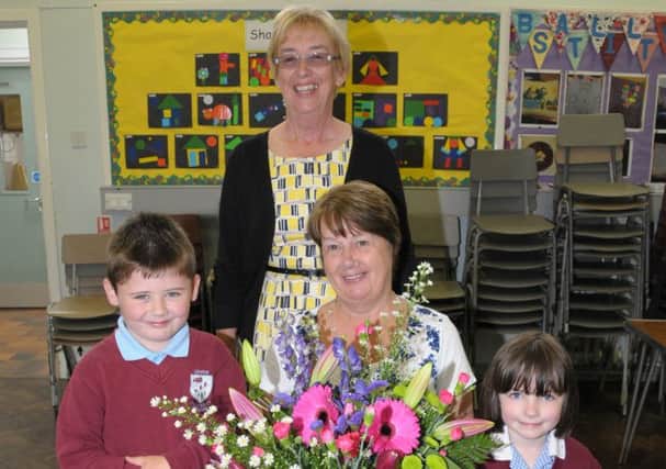 Upper Ballyboley PS classroom assistant Florence Norris, who is retiring after 19 years in the job, is presented with flowers by pupils Taylor and Alexandra. Also pictured is retiring principal Mrs Bryans  INLT 27-200-AM