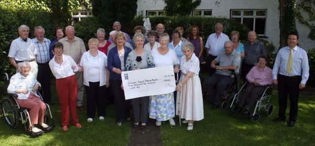 The honorary treasurer of the Dalriada branch of Parkinson's Support, Sandra Moore (fifth left) presents a cheque for £3500 to branch to Ethne Watterson MBE at the Bushtown House, Coleraine. The money was raised by Sandra from the sale of her latest book on light-hearted rhymes' Day Drams - her fifth publication. Sandra also sold items of knitwear to boost the amount.INBM28-14s