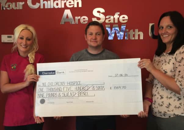 Aaron Ferguson, manager of Petite Feet Day Nursery, hands over a cheque for £1,569.70 which he raised through a sponsored abseil of the Europa Hotel in Belfast. Included are Anna McDermott (left) and Diana Lloyd. INNT 28-462-CON
