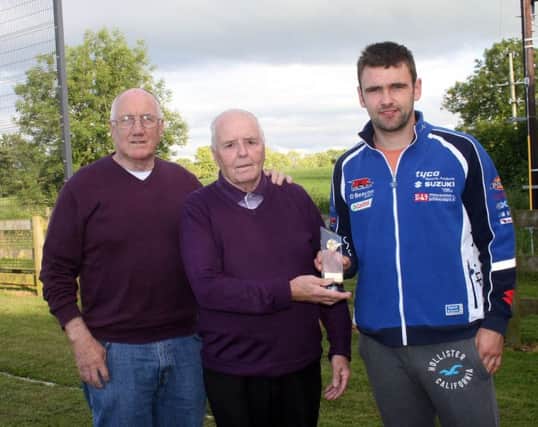 Top motor cyclist, William Dunlop, presents Sammy McNeill with a gift to mark his retirement as a referee with the LMA Summer League. Also included is tournament organiser, the irrepressible Tommy Doherty. INBM30-14 S