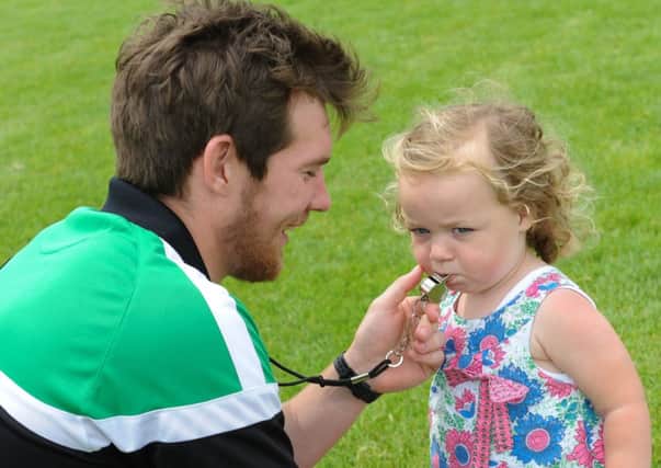 Referee at the Derrylaughan GFC Blitz and Fun Day, Sean Robinson,  gets his whistle tested by his daughter Aoibhean.