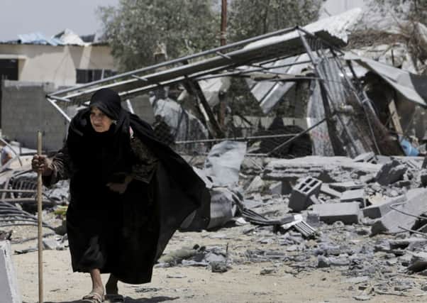 A Palestinian elderly woman walks on the rubble of her destroyed house hit by an Israeli strike in Beit Lahiya, in the northern Gaza Strip, Monday, Aug. 4, 2014. (AP Photo/Adel Hana)