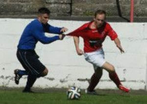 Thomas Robinson tries to escape the clutches of Ballyclare's Darren Docherty.