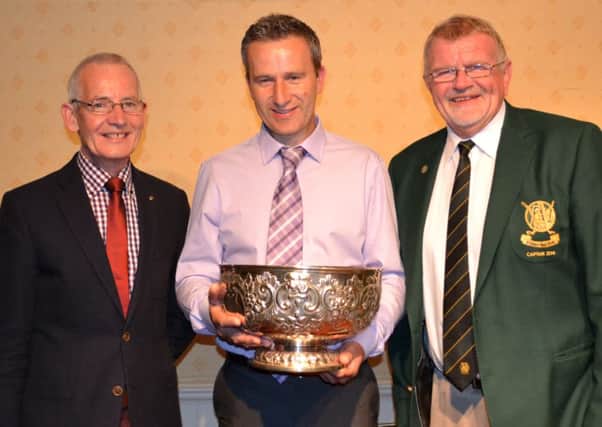 Michael Robinson holds the Barbour Cup watched by Patrick Coyle (Coyle Agencies)and Peter Cairns the Lisburn captain.
