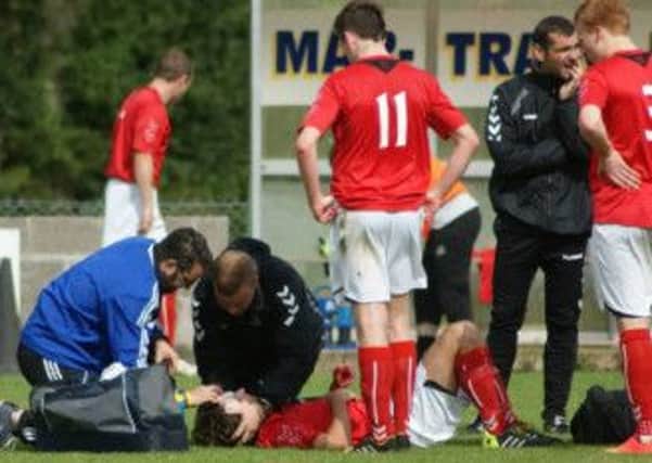 Larne's Stuart Scott receives treatment after a nasty clash of heads with team-mate Owen Thompson. Photo: Andrew Scullion.