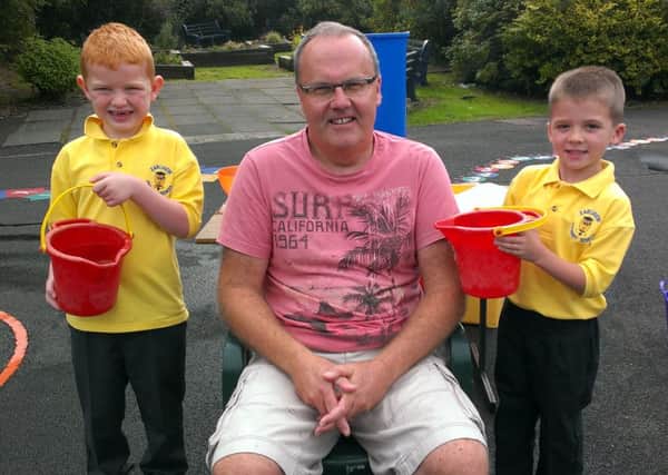 Earlview PS pupils Charlie McClenaghan (left) and Daniel Stewart are only too happy to give principal Raymond Smyth a helping hand with his ice bucket challenge. INNT 37-510CON