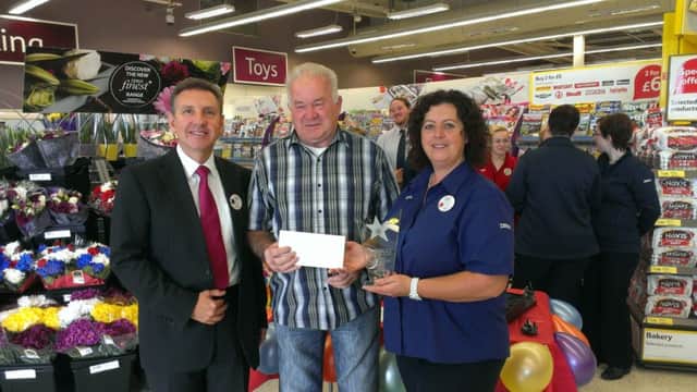 Tesco Community Champion Bobby Davis receives his prize from Tesco Ballymoney store manager Geoff Purcell and Tesco community champion Jackie Brogan. INBM38-14 UC