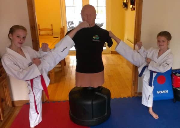 Jodie and Jessie McKew practice their taekwando skills on their training dummy Bob.
