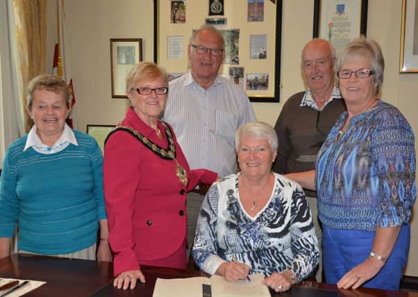 Brenda Collier, from Winnipeg, Manitoba, Canada, signs the visitos book at a reception hosted by Mayor of Ballymena Cllr Audrey Wales at the Braid Town Hall. Looking on are Brenda's Ballymena cousins Iris McFetridge, Robert Kidd, James McFetridge and Avril Kidd. INBT 40-