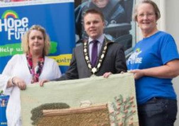Kyla Graham, left, receiving the tapestry from Newtownabbey mayor Alderman Thomas Hogg.  Also pictured is Hope and a Future charity shop manager Jane Holmes.  INCT 40-738-CON