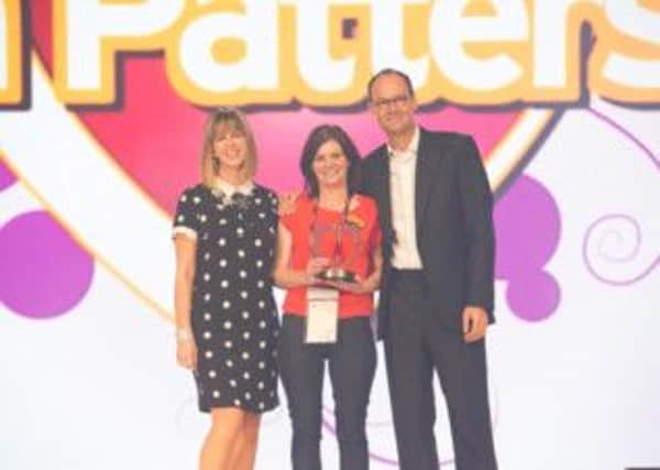 Anne receiving her Community Champion award at the Sainsburys Colleague Conference from Chief Executive Mike Coupe and presenter Kate Garaway.  INCT 41-732-CON