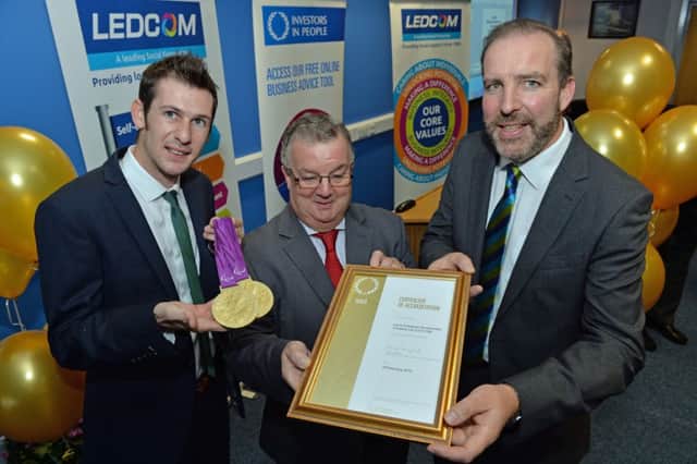 Paralympian, Michael McKillop shows off his gold medals as Ken Nelson CE of Ledcom receives a certificate of accreditation for acheiving the Ivestors in People Gold Award from Bill Gordan, Assesment Manager from DEINI. INLT 41-009-PSB