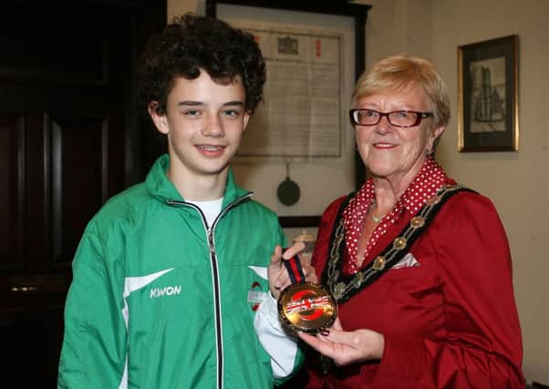 Local kickboxer Ryan Sharp, winner of the gold medal from the World Kickboxing and Karate Union championships in London, is pictured showing off his medal to the Mayor of Ballymena, Cllr. Audrey Wales, at a special reception in The Braid. INBT40-230AC