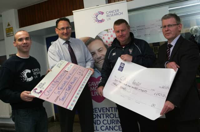 Paul McBride, rugby captain, presenting a £6,923.00 cheque to Cancer Research UK's Mark McMahon and Richard Beggs presenting a £6,923.00 cheque to Dr. David Carutthers.