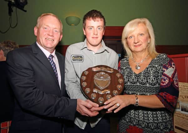 Ballymena couple Steven and Janet Redmond present the Isobel Matthews Memorial Shield to Special Olympics wiinner Dale Moore during the Markethill Festival presentation of cheques recently. Isobel , from Kells, was formerly in charge of the Northern Ireland Special Olympic movement. INPT41-1158
