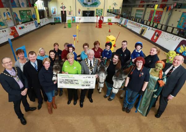 Cheque hand over: Deputy Mayor of Newtownabbey, Alderman Pat McCudden (centre) and Mayor of Antrim, Cllr Brian Graham (left) with Asda representatives, volunteers and members of The Donkey Sanctuary Assisted Therapy Centre Parents and Friends Association and children from Riverside School.