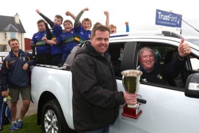 The victorious Lisburn team celebrate on the back of a Trust Ford vehicle while their coach is presented with the trophy after steering his young side  to success at the 10th annual mini-rugby festival, hosted by Dromore Rugby Club.