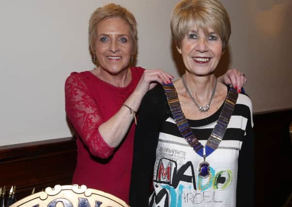 Outgoing president Anne Henry hands over the chain of office to new president Maureen Baw at last week's Lions Club meeting in the Adair Arms Hotel. INBT 50-107JC