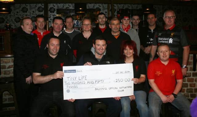 Chris McAuley from Tiny Life accepts a cheque for £250 from officials and members of Ballycastle Official Liverpool Supporters' Club at The Anzac Bar. Included are Hilary Midgley, chairperson, Damian O'Kane, secretary, Adrian O'Boyle, treasurer and members of the club. The money was raised from a table quiz held in The Anzac. INBM50-14S