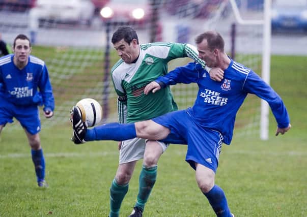 Rathfern's Craig McMurdie gets there ahead of St Patrick's YM captain, Keith Mulvenna. Photo: Philip McCloy.