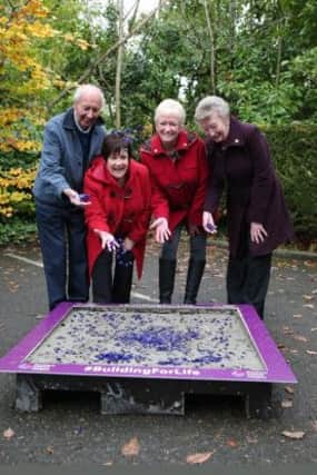 NI Hospices Carrickfergus support group members drop purple pebbles into a cement slab which will form part of the new Hospice.   INCT 48-720-CON