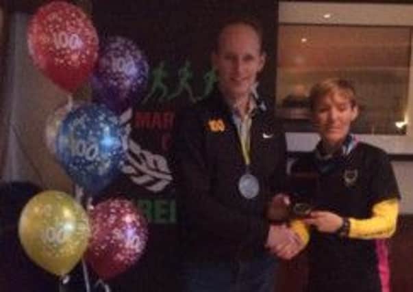 Seapark AC chairperson Valerie Fogarty presents Gary Connolly with his 100th Marathon medal.