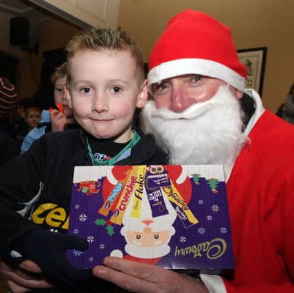JAKE TAKES. Young Jake looks pleased to receive a selection box from Santa Claus at the Mini/Maxi rugby event on Saturday morning at BRFC.INBM51-14 118SC.